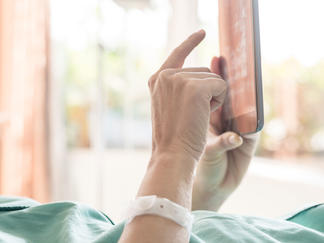 Patient in hospital room using a tablet.